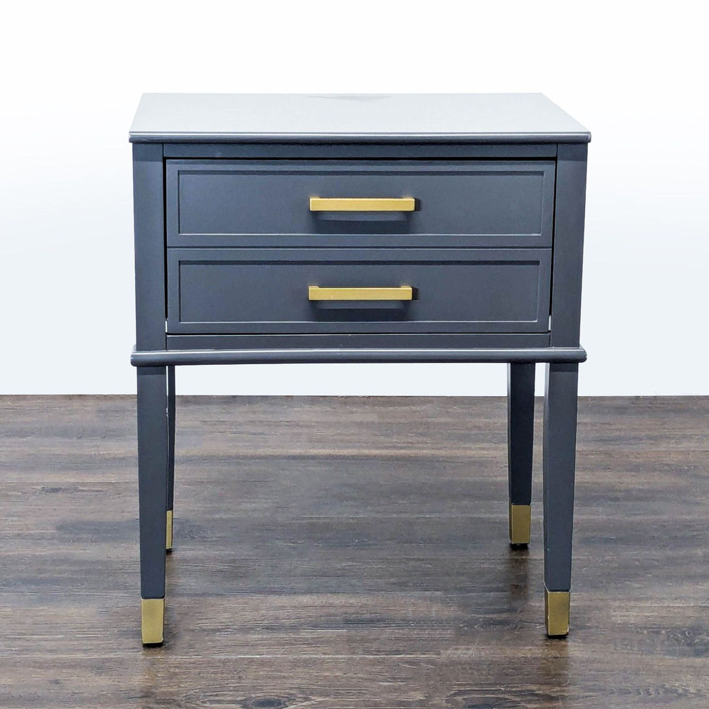 1. Gray CosmoLiving by Cosmopolitan end table with two drawers and gold handles, set on a wooden floor.
