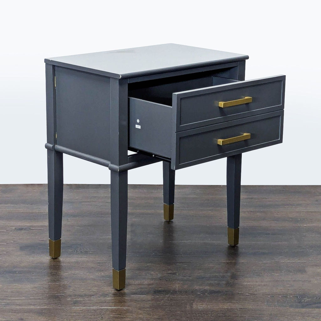 2. Angled view of a CosmoLiving by Cosmopolitan end table showing one open drawer, gold accents on legs.