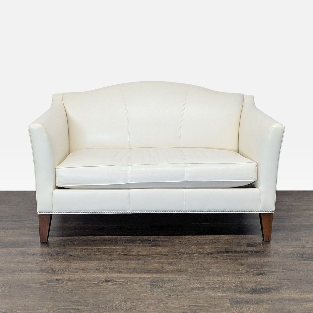 Ethan Allen cream leather loveseat with silver nailhead trim and wood legs, ideal for small spaces.