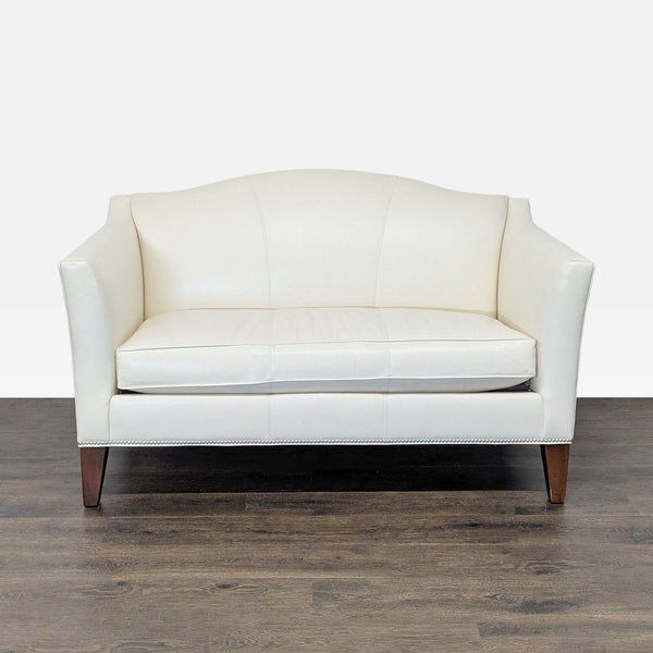 Ethan Allen cream leather loveseat with silver nailhead trim and wood legs, ideal for small spaces.