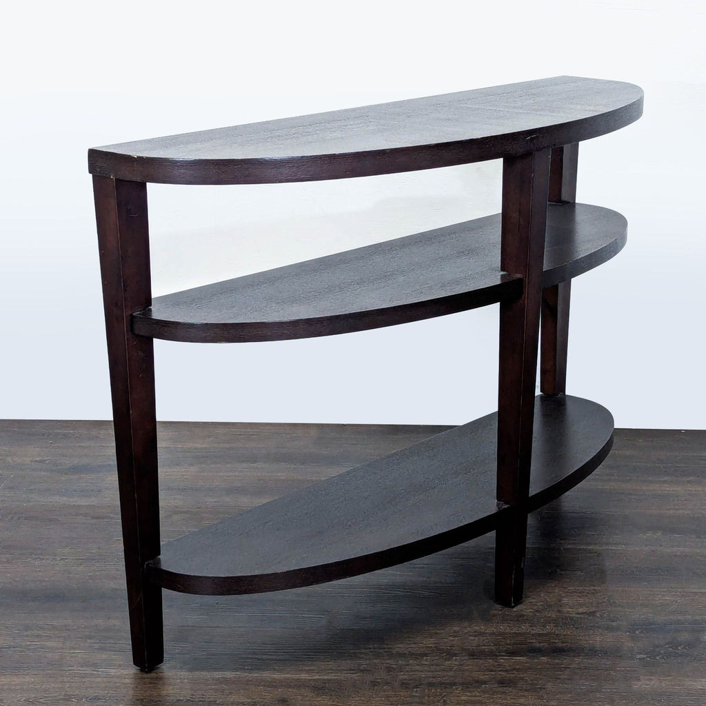 2. Angled side view of a semi-circular dark wooden side table with three open shelves for display or storage.  
