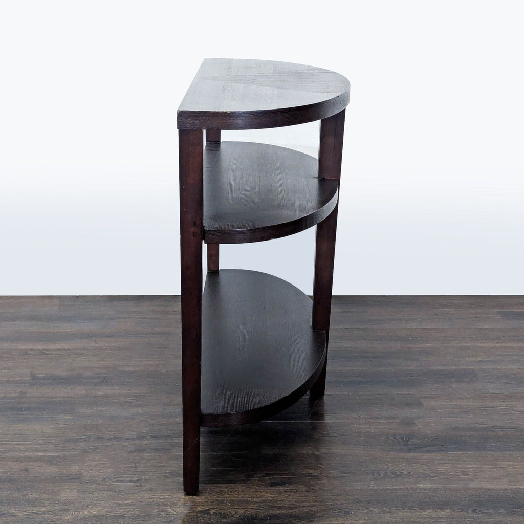 3. Side profile of a three-shelf, dark wood console table with a semi-circular design and simple straight legs.