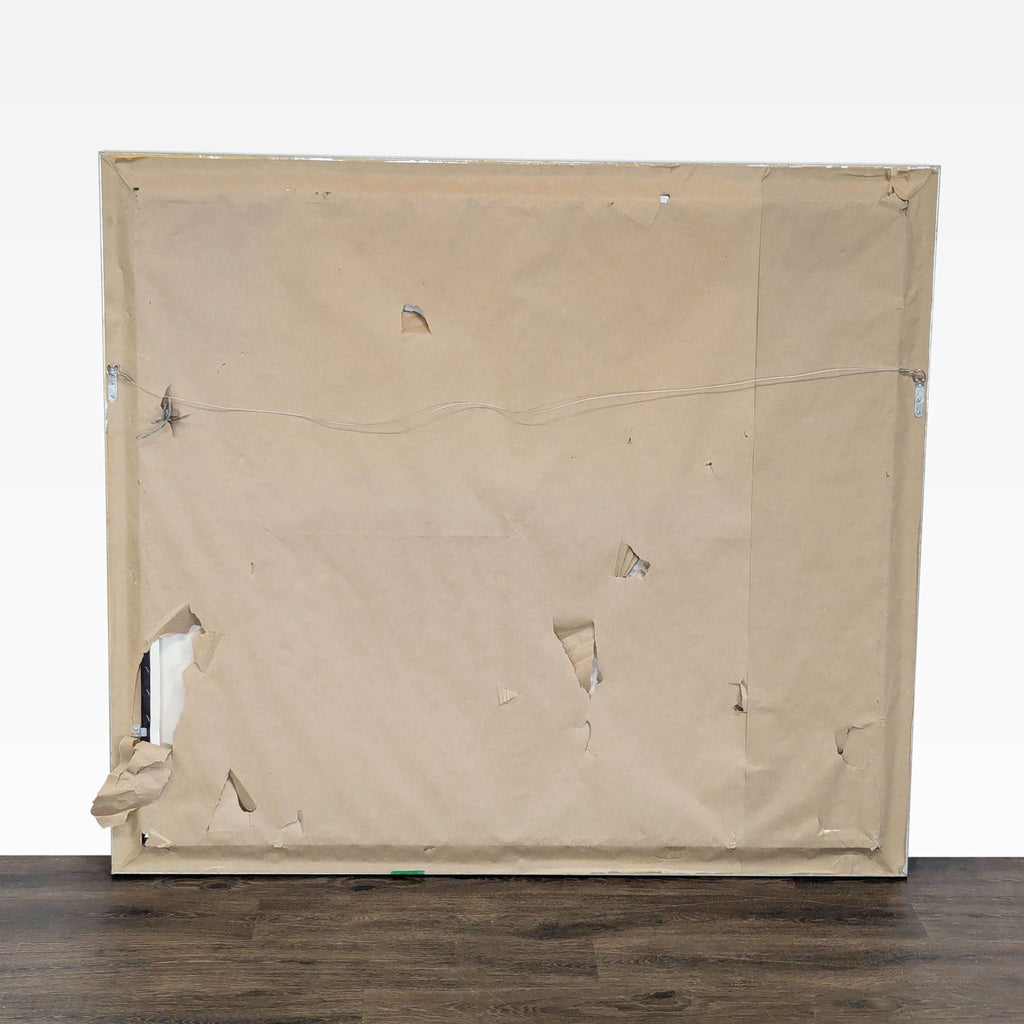 3. Back of framed print with torn brown paper backing and visible hanging wire; item by Craig Tracy.