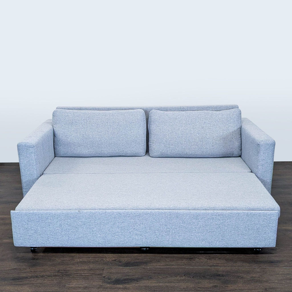 Contemporary sleeper sofa in light gray fabric, designed for comfort and versatility in apartments or guest rooms.  