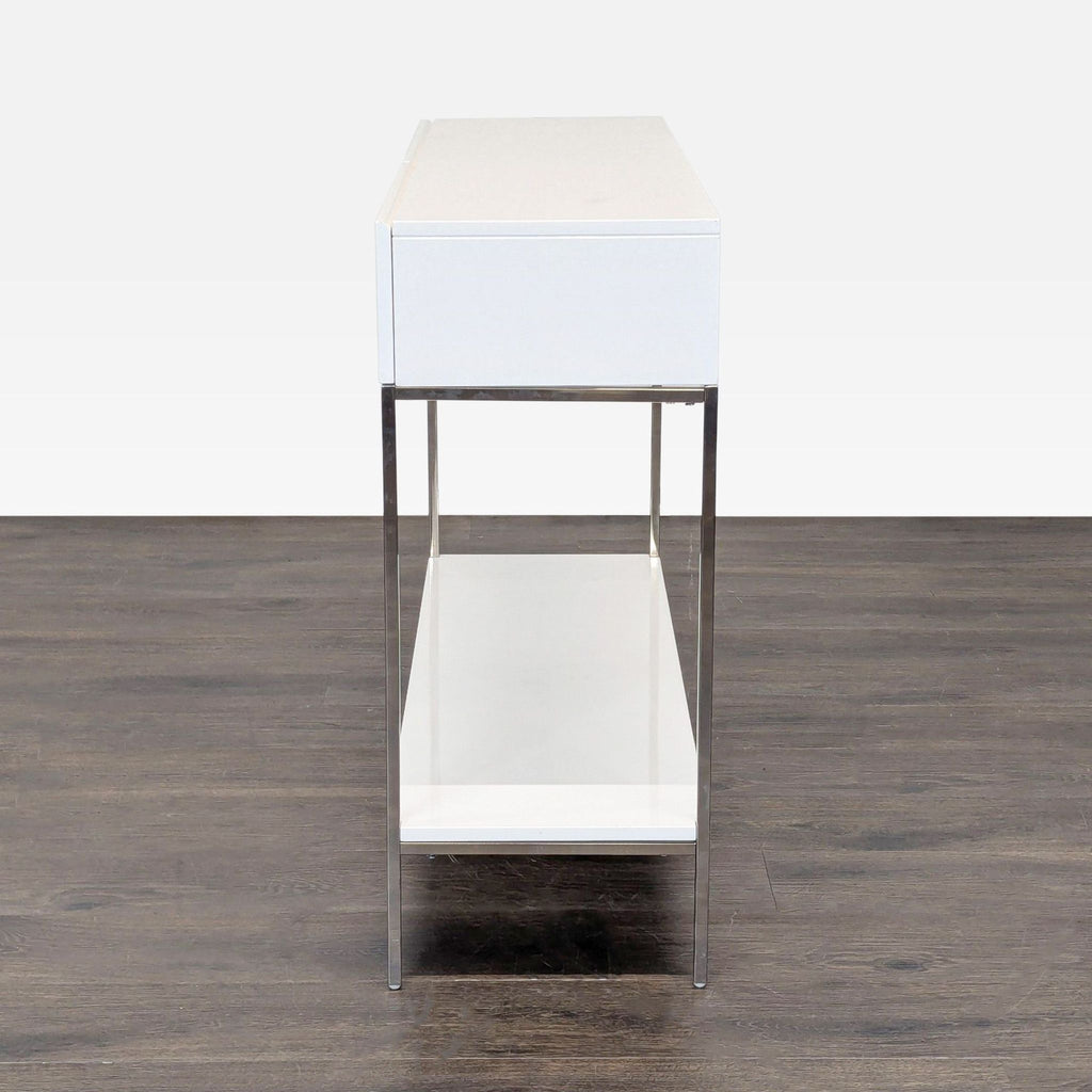 3. Minimalist West Elm console table in white with chrome legs, slim side profile and open lower shelf.