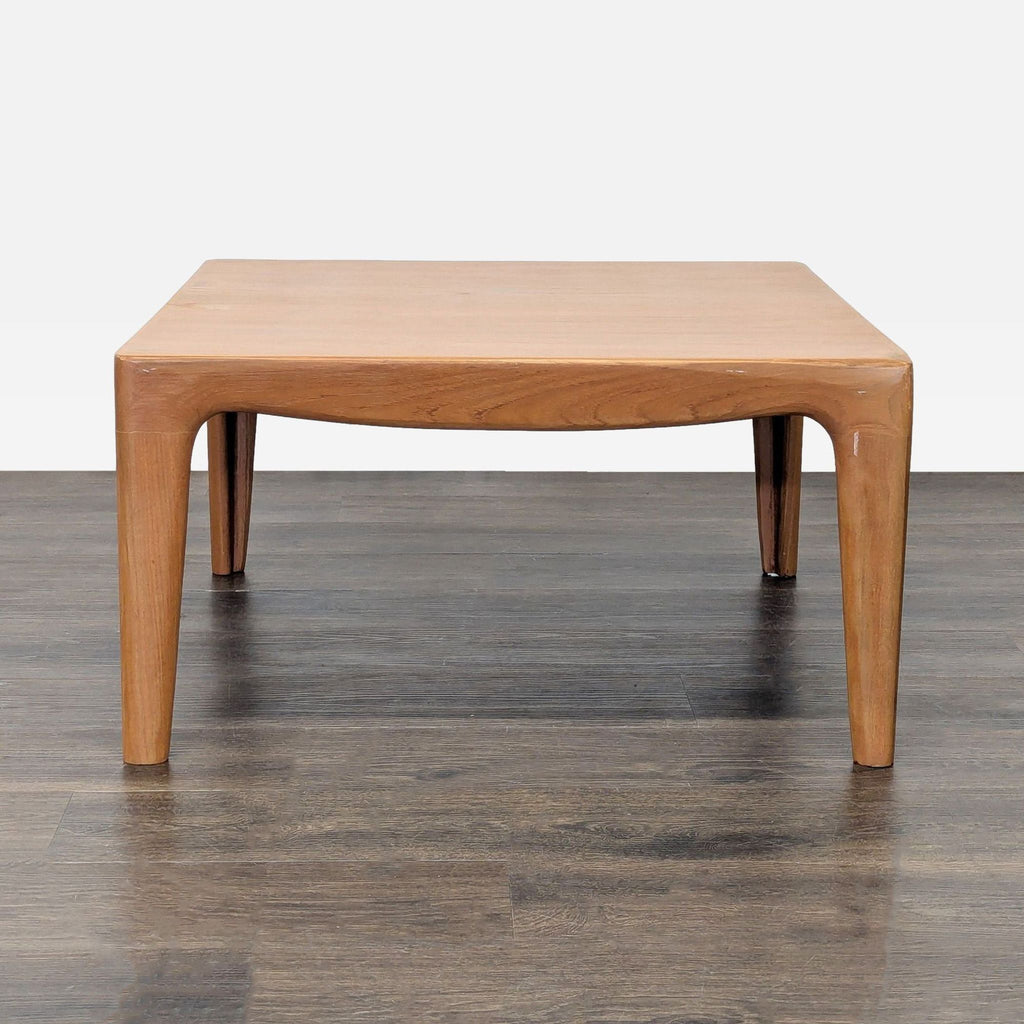 1. Square wooden coffee table with rounded edges and tapered legs on a dark wood floor, front view.