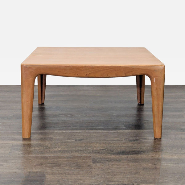 1. Square wooden coffee table with rounded edges and tapered legs on a dark wood floor, front view.