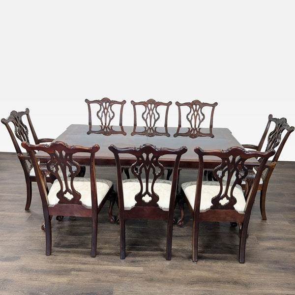 Polished mahogany dining set with a large table, two leafs, and eight carved chairs with upholstered seats.