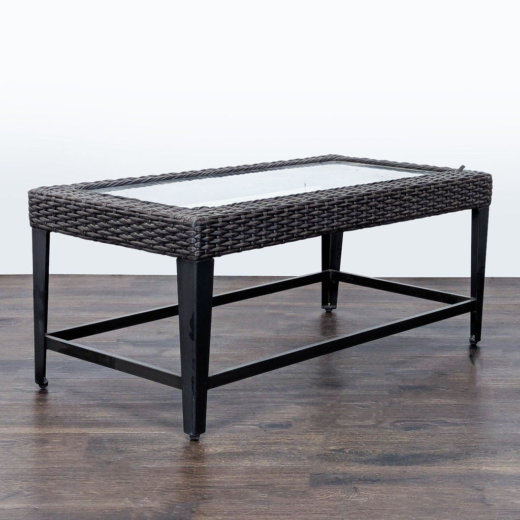Modern table featuring a clear glass surface, sturdy metal base, and decorative wicker trim for versatile use.  