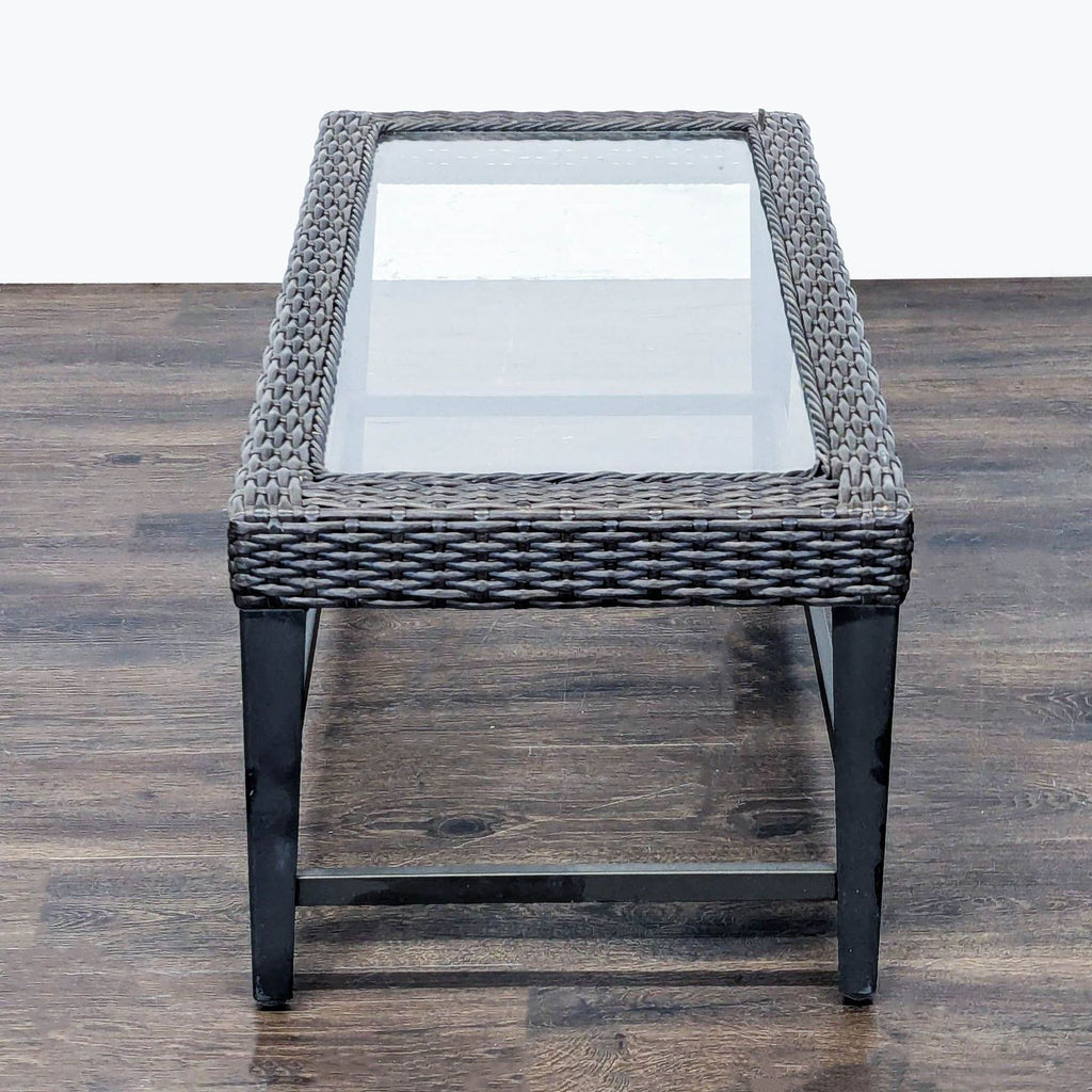 Stylish rectangular table with glass top and woven wicker border, ideal for patios, gardens, or living rooms.