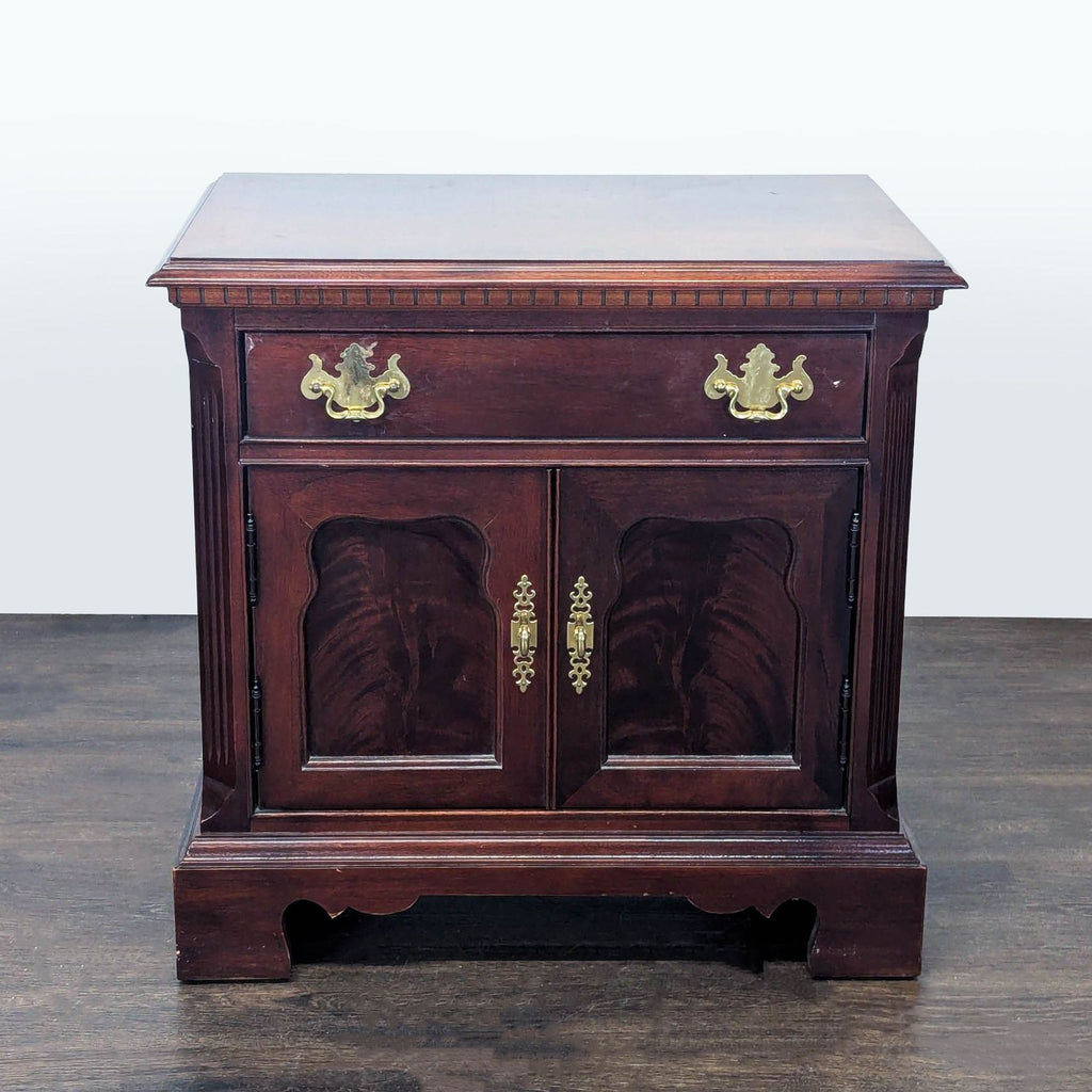 Thomasville end table with one drawer, fluted pilasters, brass hardware, and recessed flame mahogany doors.