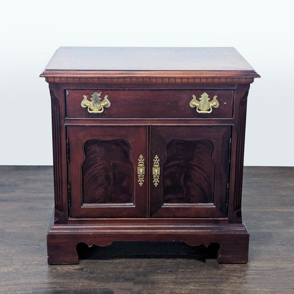 Thomasville end table with one drawer, fluted pilasters, brass hardware, and recessed flame mahogany doors.