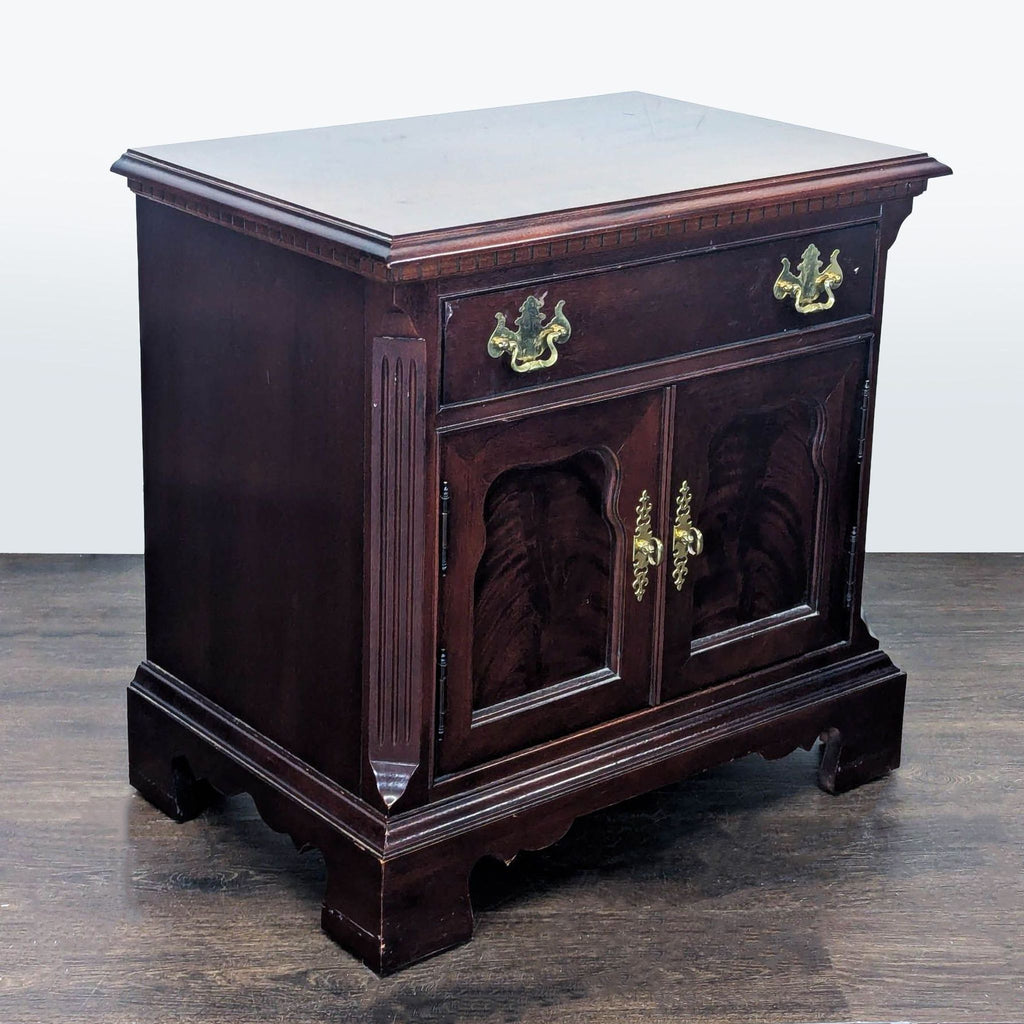 Flame mahogany Thomasville end table with brass hardware, fluted sides, and distinctive cabinet door detailing.