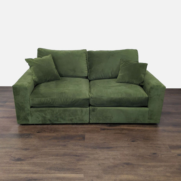 Green faux suede loveseat with boxy design, firm cushions, and two matching throw pillows.
