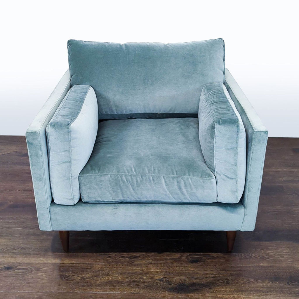 Light blue velvet lounge chair with plush cushions and wooden legs, showcasing a modern design.  