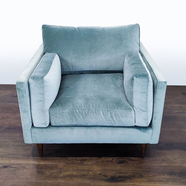 Light blue velvet lounge chair with plush cushions and wooden legs, offering a cozy, modern look.