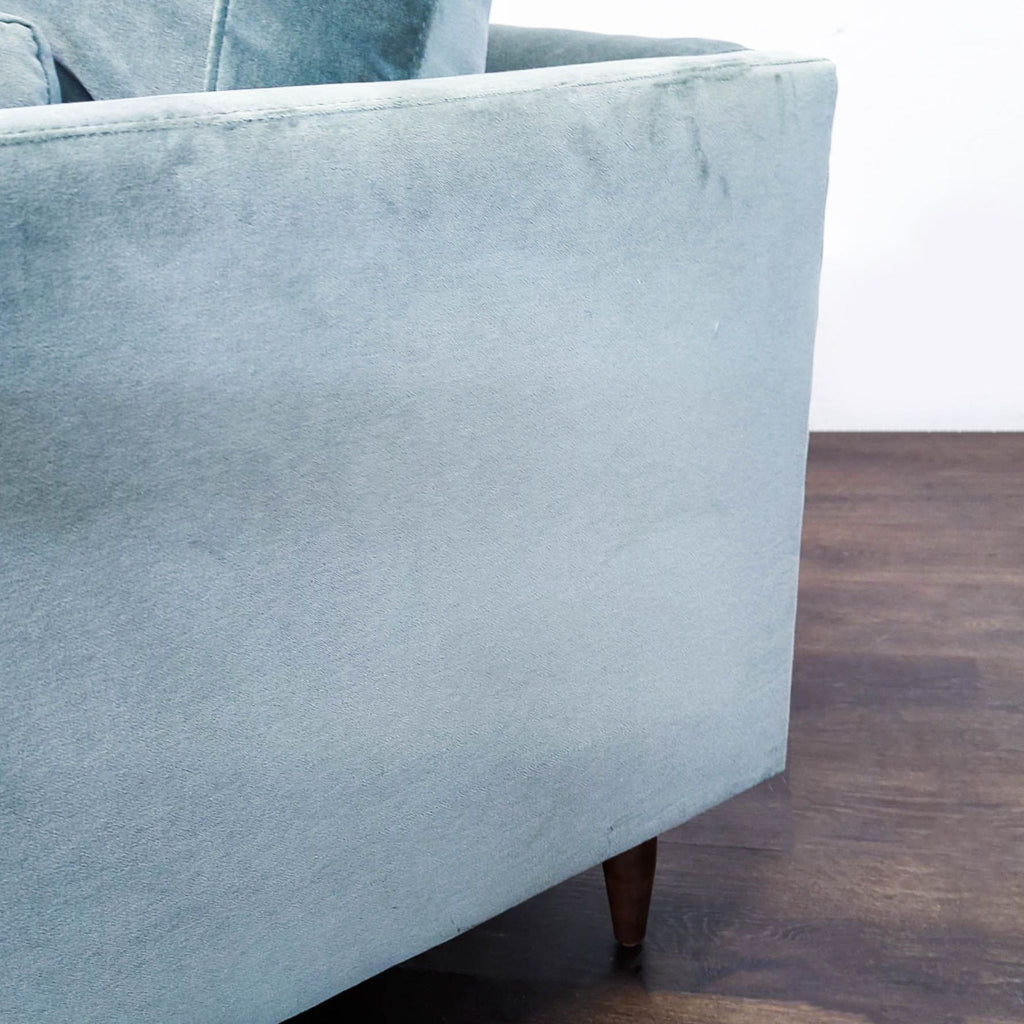 Plush light blue velvet chair with clean lines and wooden legs, ideal for relaxing in a lounge area.