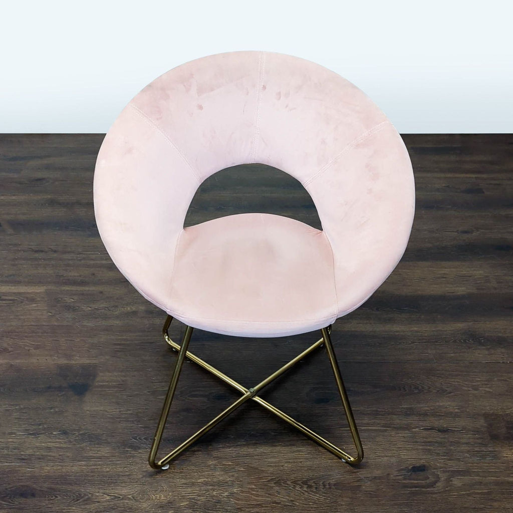 1. Circular pink velvet lounge chair with an open-back and gold metal legs on a dark wood floor.