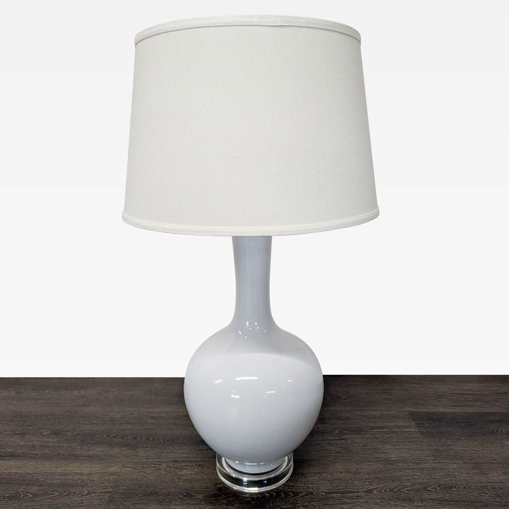 Two matching Safavieh white ceramic lamps with drum shades on clear stands, suitable for any décor style.