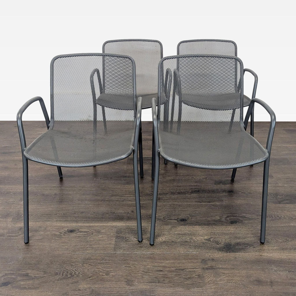 Set of four Room & Board metal chairs with armrests and mesh design, ideal for indoor or outdoor spaces.