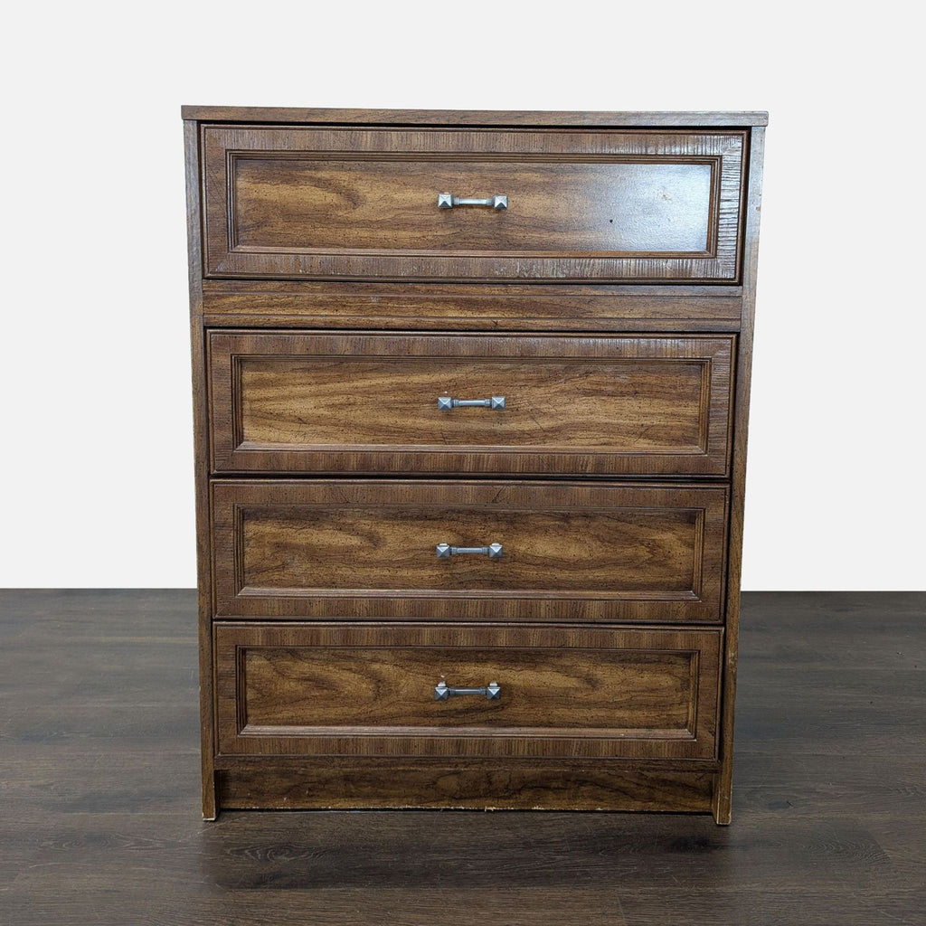 Front view of a classic brown wooden dresser with four drawers and silver handles, standing on a wood floor.