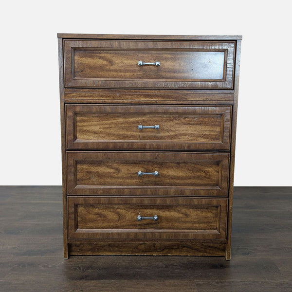 Front view of a classic brown wooden dresser with four drawers and silver handles, standing on a wood floor.