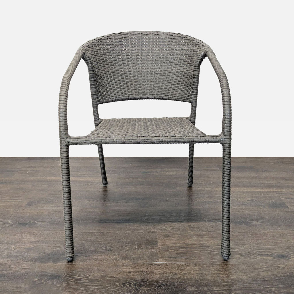 Single woven patio chair with curved arms and a simple modern design, displayed on wood flooring.