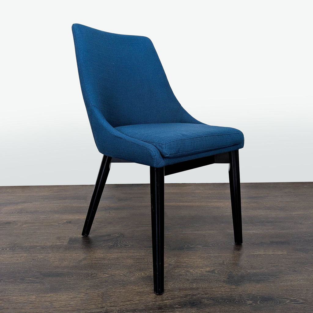 2. Angled side view of a blue Modway dining chair, featuring a cushioned seat and black legs on a wood floor.