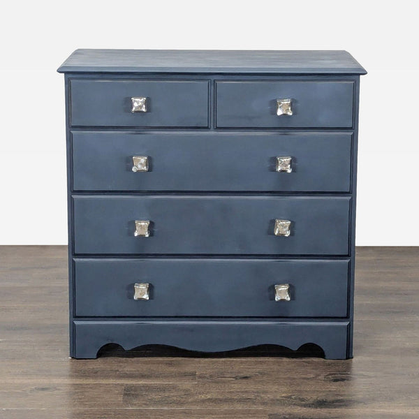 Navy blue dresser with five drawers and crystal-style knobs, offering ample bedroom storage.