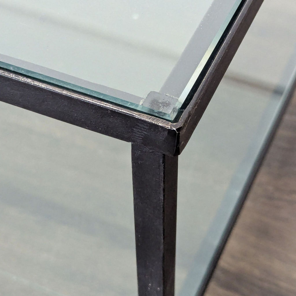 2. Close-up of coffee table corner showing glass top and sturdy black metal frame.  