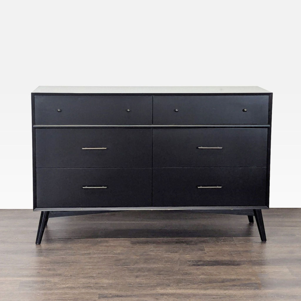 Sleek black six-drawer dresser by Living Spaces with metal handles and angled legs, ideal for bedroom storage.