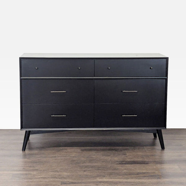 Sleek black six-drawer dresser by Living Spaces with metal handles and angled legs, ideal for bedroom storage.