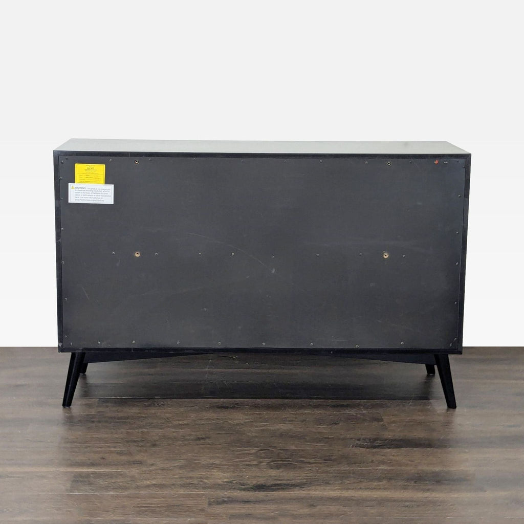Black dresser from Living Spaces featuring six drawers, sturdy handles, and angled legs, perfect for any room.