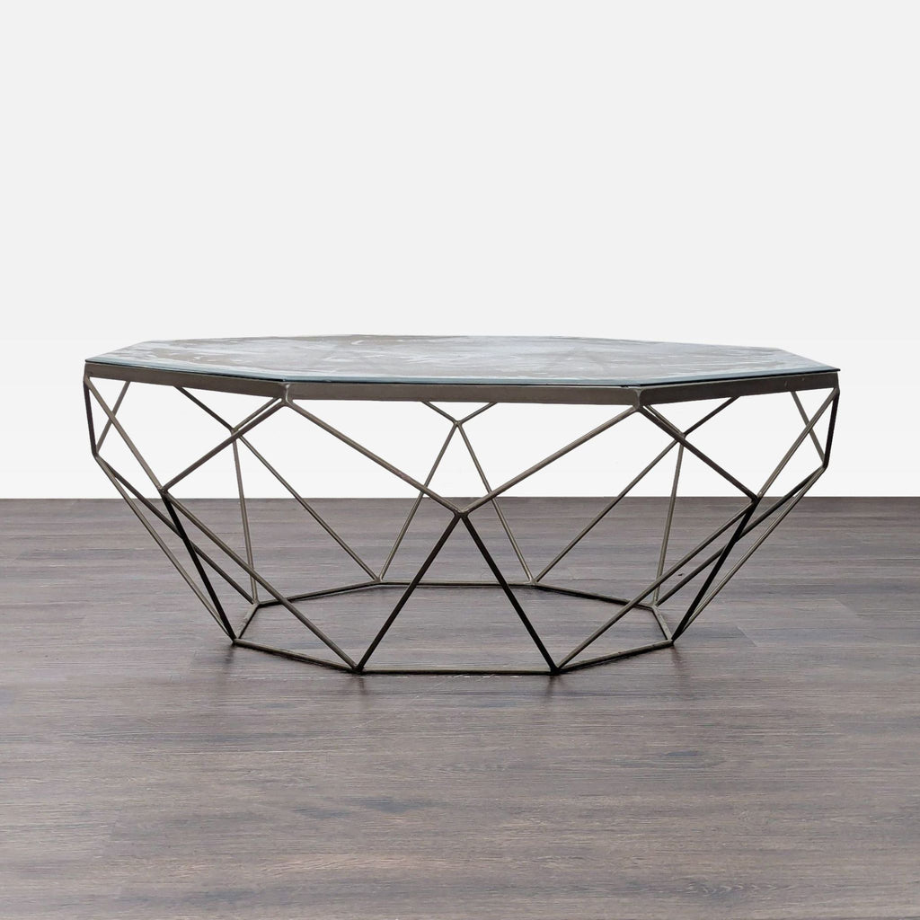 Geometric metal coffee table with a glass top, featuring an angular, modern wireframe base.