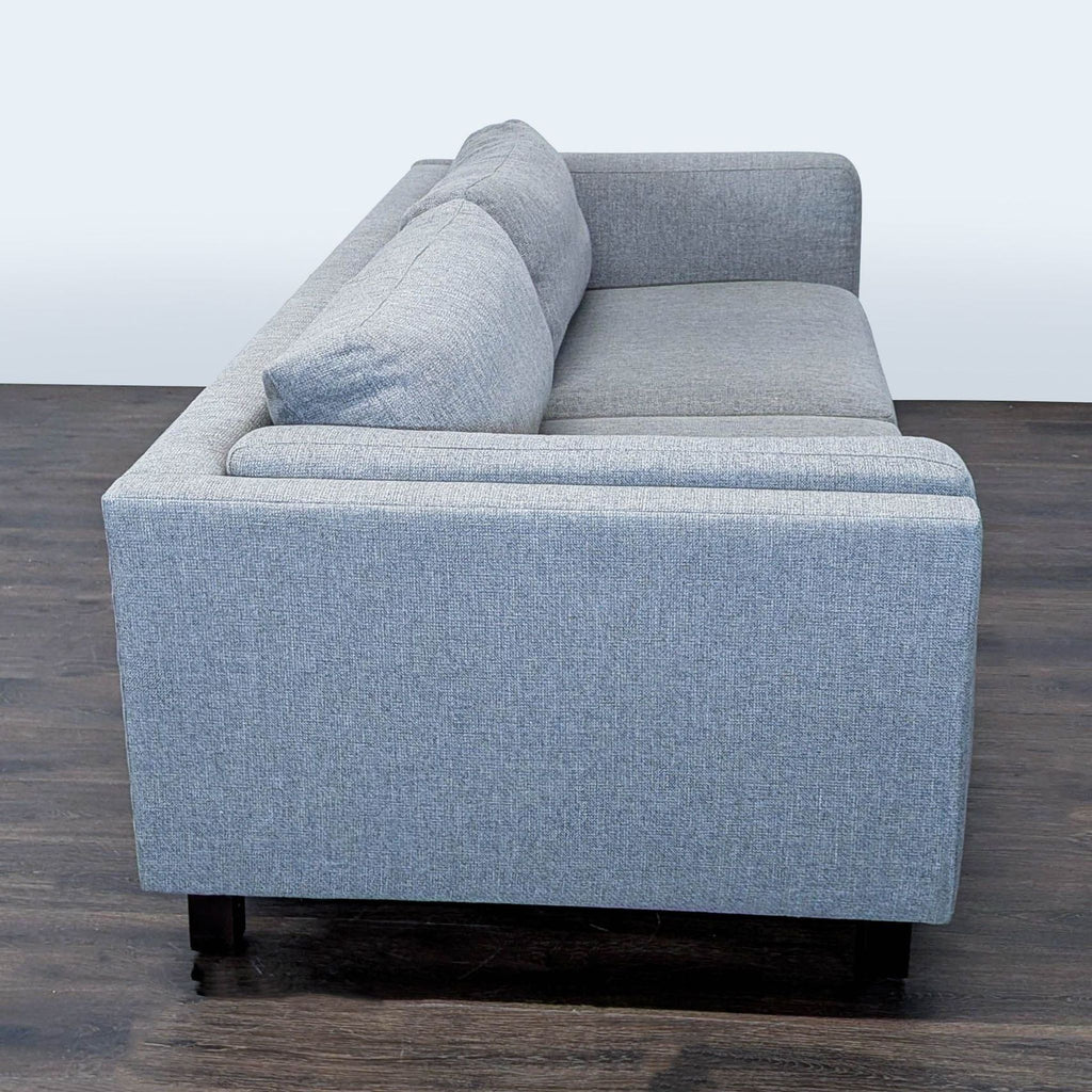Three-seat Room and Board sofa in soft gray fabric, featuring a sleek design and durable wood legs.