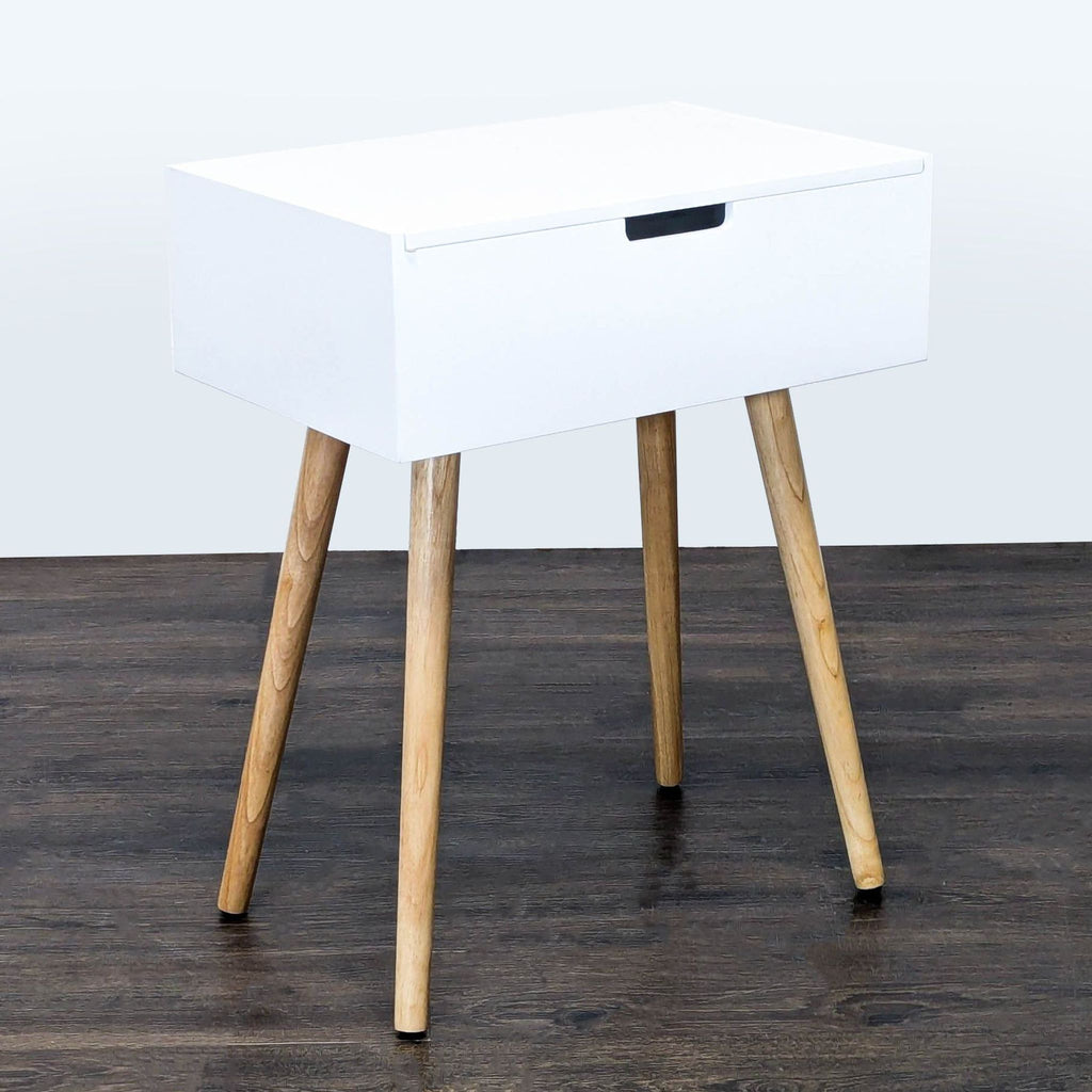3. Sleek white side table with storage, angled wood legs and a closed hinged lid, suitable for various uses.
