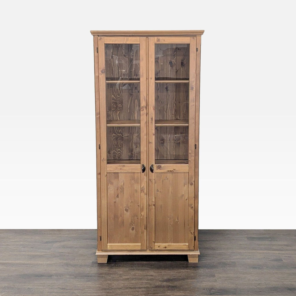 1. Tall wooden cabinet with glass-paneled double doors, shown closed on a wood floor, in the Cabinet category.