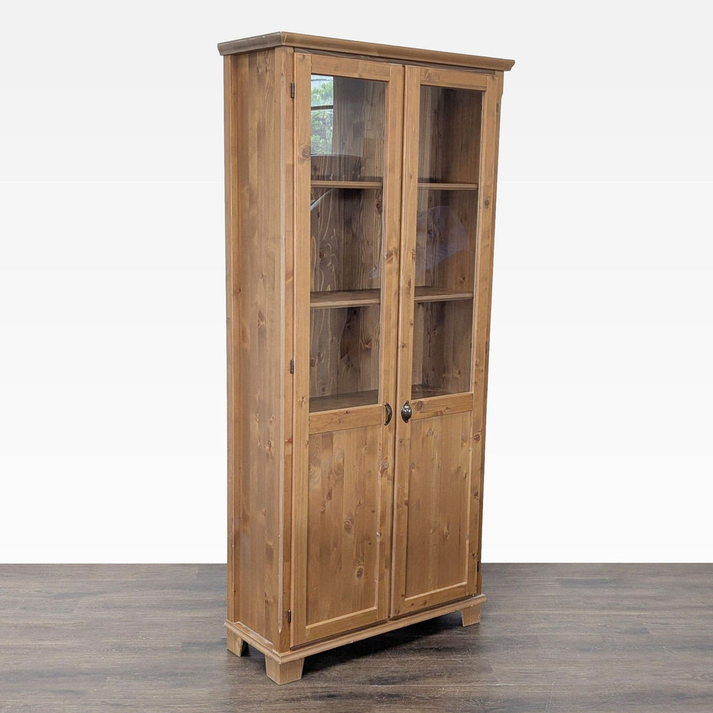 3. Angled view of a wooden cabinet with glass doors and metal handles, designed for storage or display use.