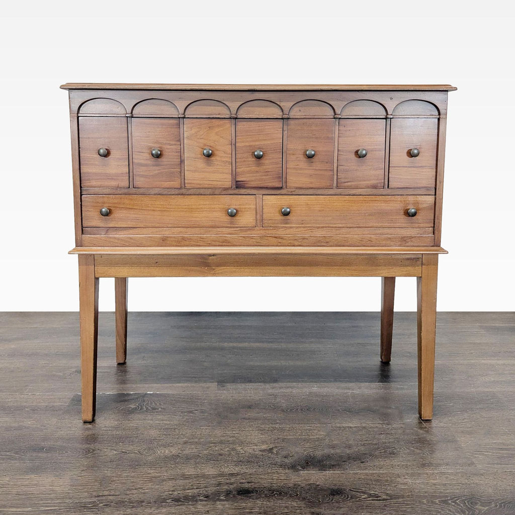 Front view of a wooden nine-drawer sideboard server with simple round knobs and lined silverware section.  