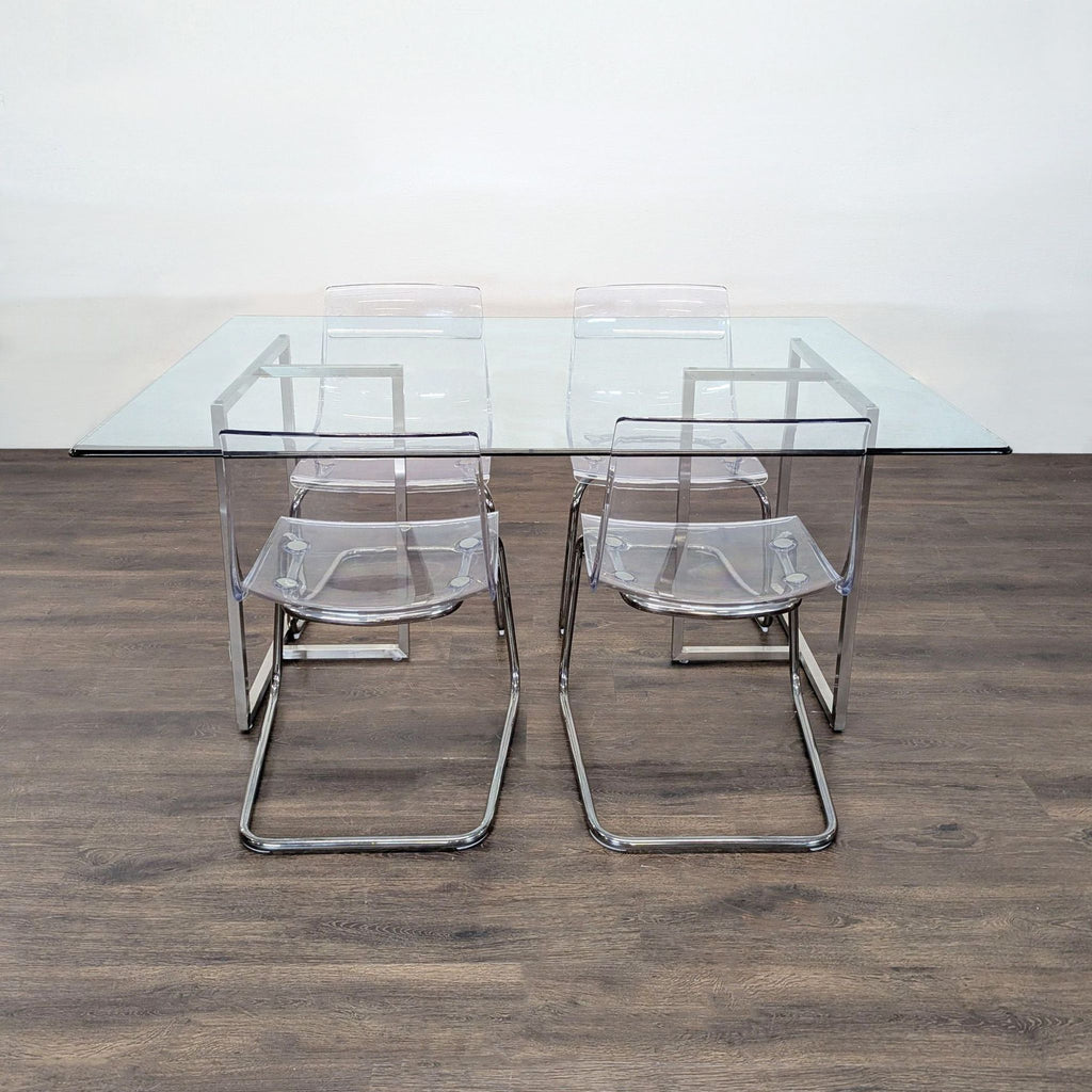 Modern dining set with glass table and four clear acrylic chairs on a metal frame.