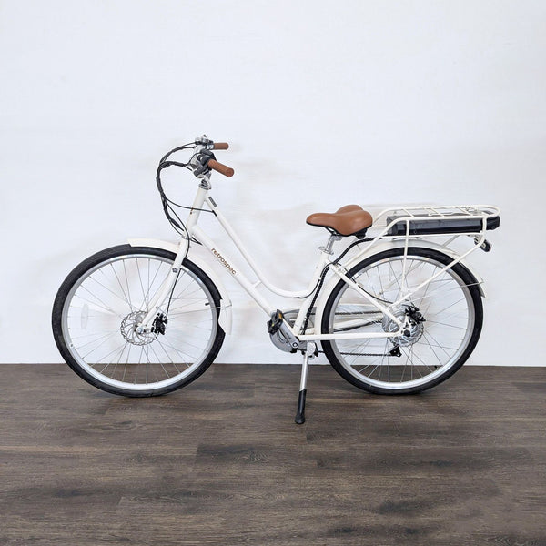 Retrospec electric city bike with a step-through frame, brown saddle, and rear rack for easy city rides.