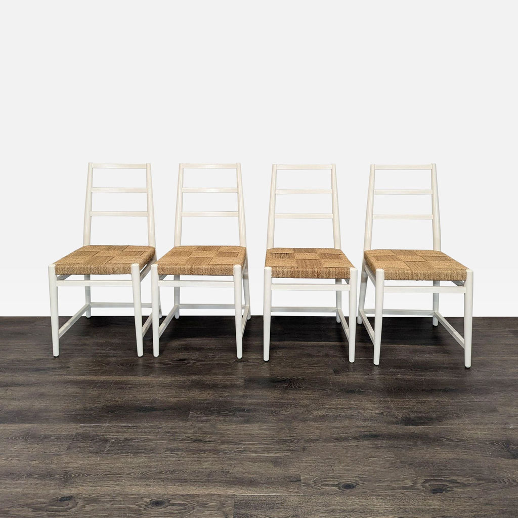 Set of four white dining chairs with ladder backs and woven natural fiber seats arranged in a row.