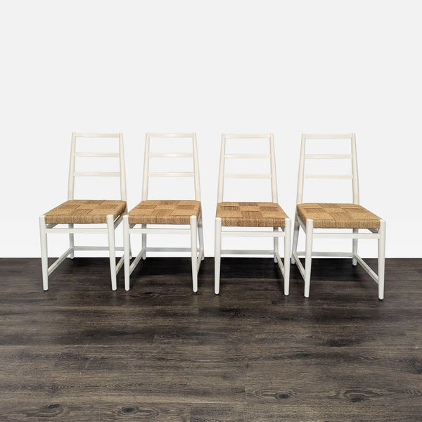 Set of four white dining chairs with ladder backs and woven natural fiber seats arranged in a row.