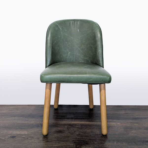 1. Green upholstered dining chair with curved backrest and wooden legs, front view on dark wood floor.