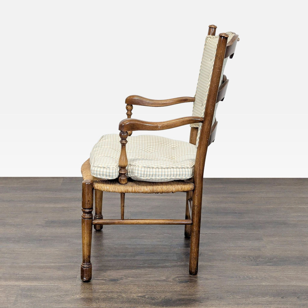 Side view of a Country French dining chair with cushioned button-tufted gingham seat and back, and carved wooden arms.