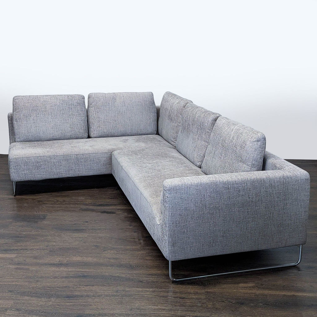 Gray L-shaped sectional by Benson Canyan, featuring sleek metal legs and ample seating for living or family rooms.  