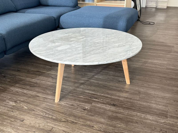 1. Round marble coffee table by Article with light wooden legs, placed on dark wood flooring near a blue sofa.