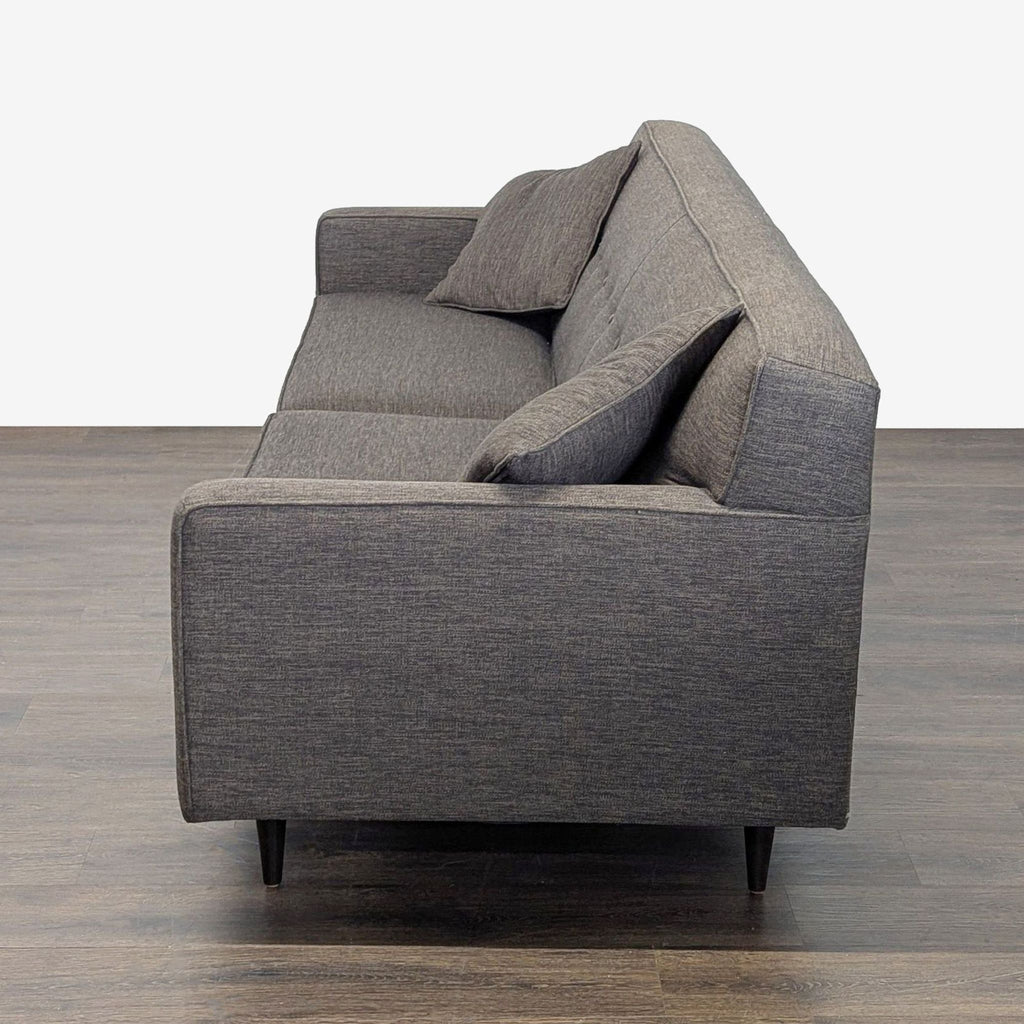 Sleek 3-seater sofa with sturdy wooden legs, dark grey upholstery, straight lines, and matching cushions.