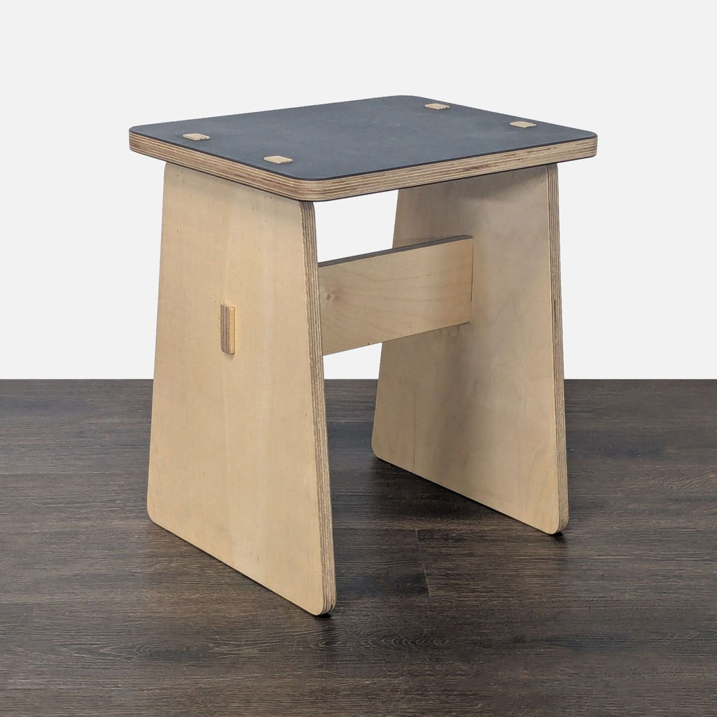 2. Angled view of a modern console table with a dark top and natural plywood sides, placed on wood flooring.  