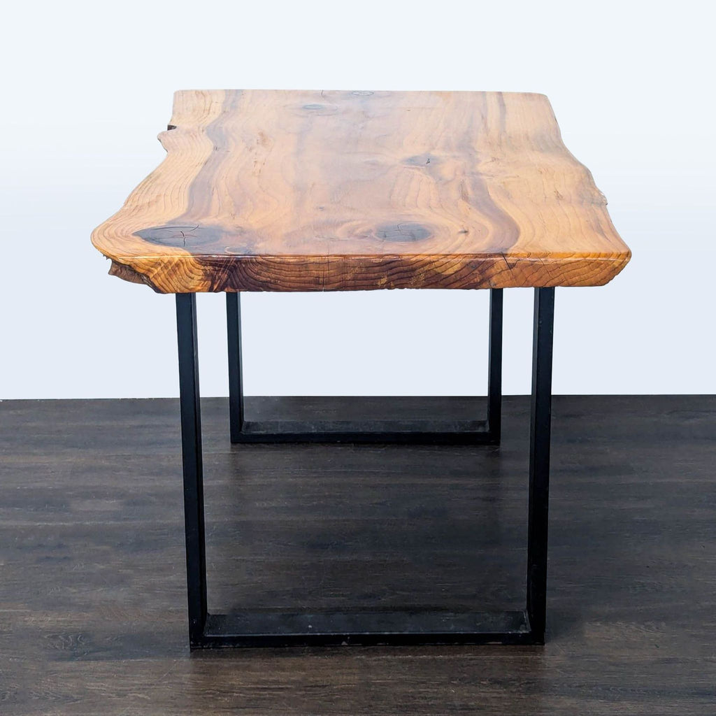 Handcrafted wooden dining table features an organic edge and sturdy black steel legs, shown from the end view.